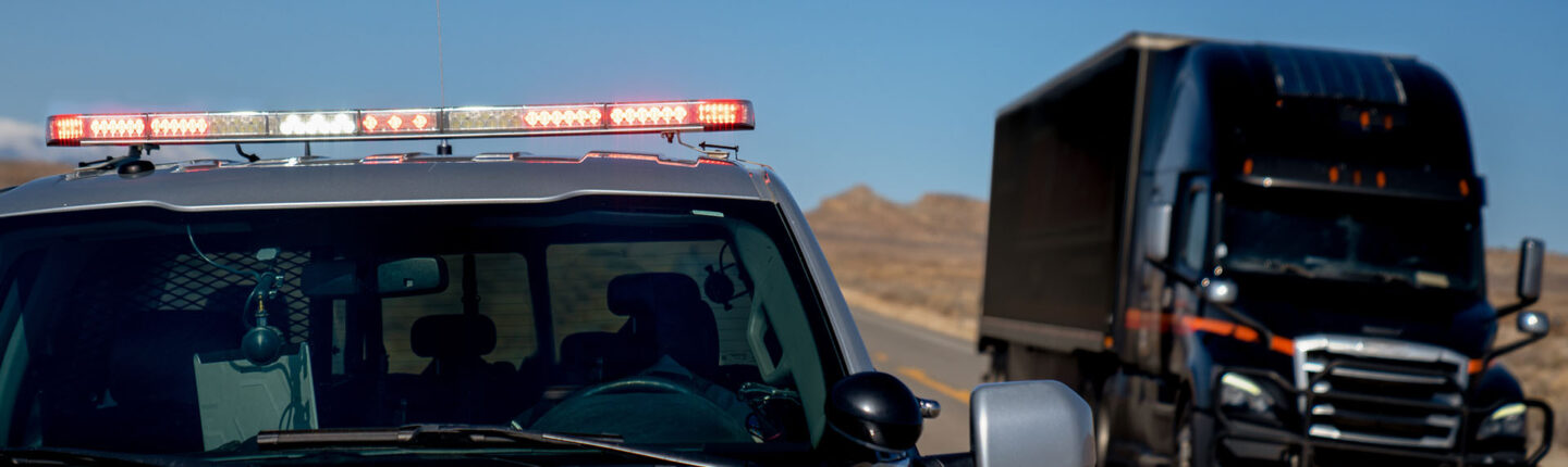 Une voiture de patrouille avec des feux clignotants est retirée de l'épaule pour donner un ticket au conducteur alors qu'un semi-camion passe par